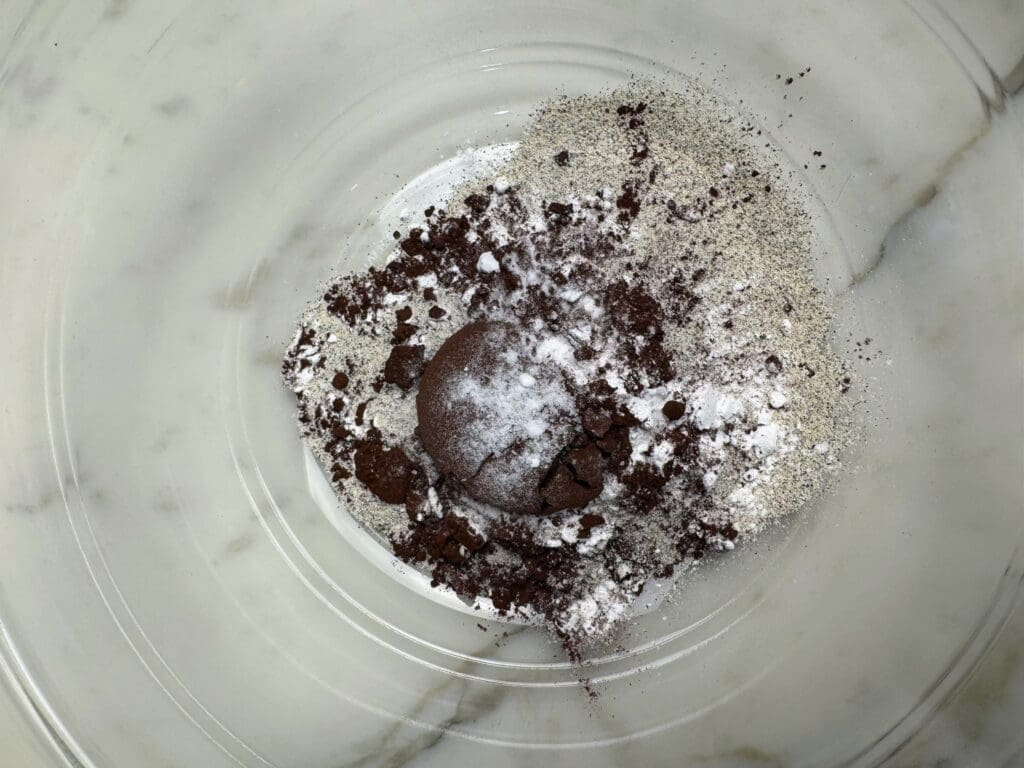 Dry ingredients for plant-based chocolate mug cake in glass mixing bowl showing buckwheat flour, tapioca flour, cocoa powder, baking soda and salt before mixing