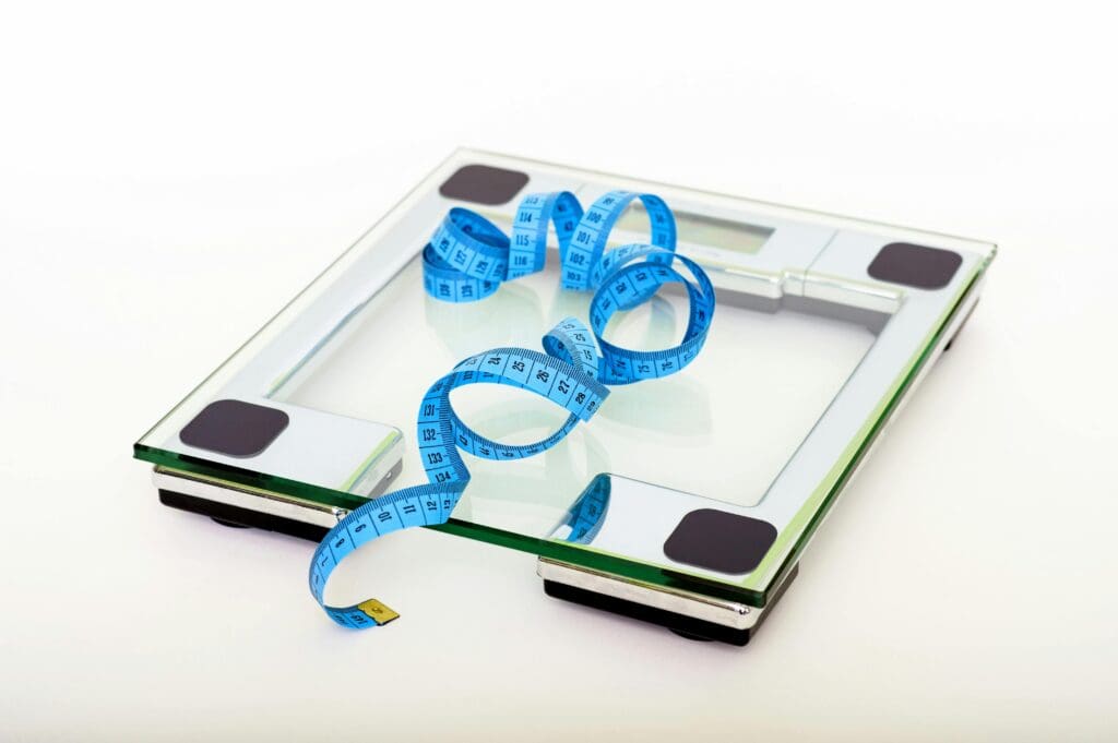 Digital bathroom scale with blue measuring tape representing 5 pounds of weight loss achieved during 7-day wellness retreat experiment