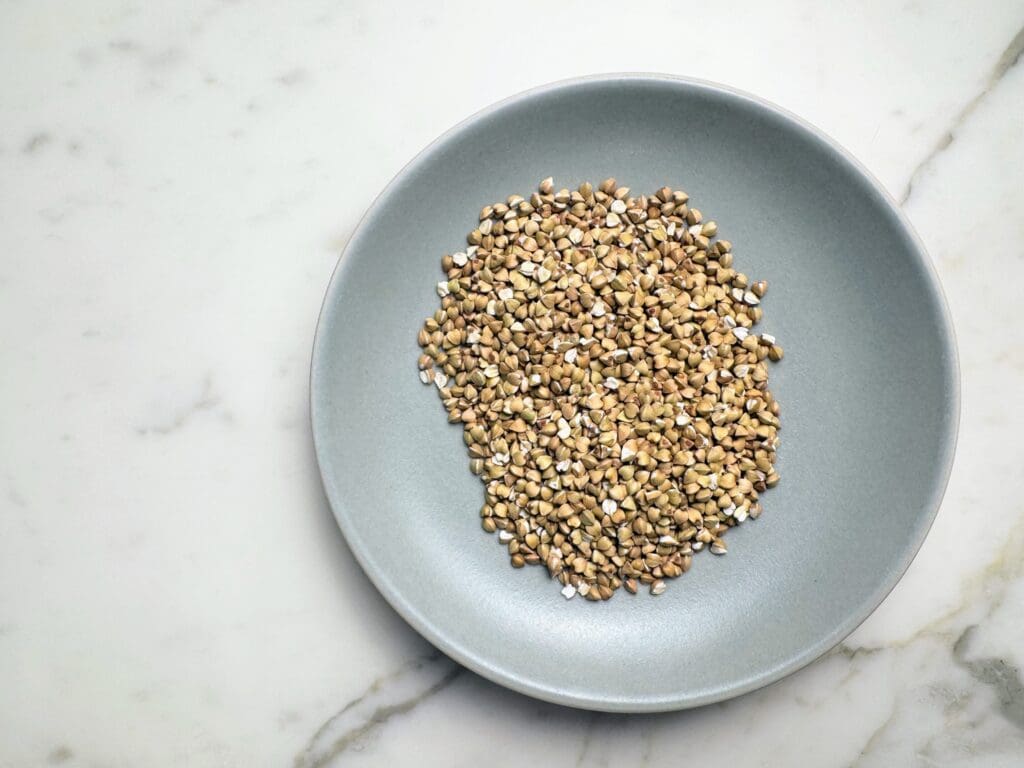 Raw buckwheat groats in bowl showing triangular whole grain kernels as oat groat alternative