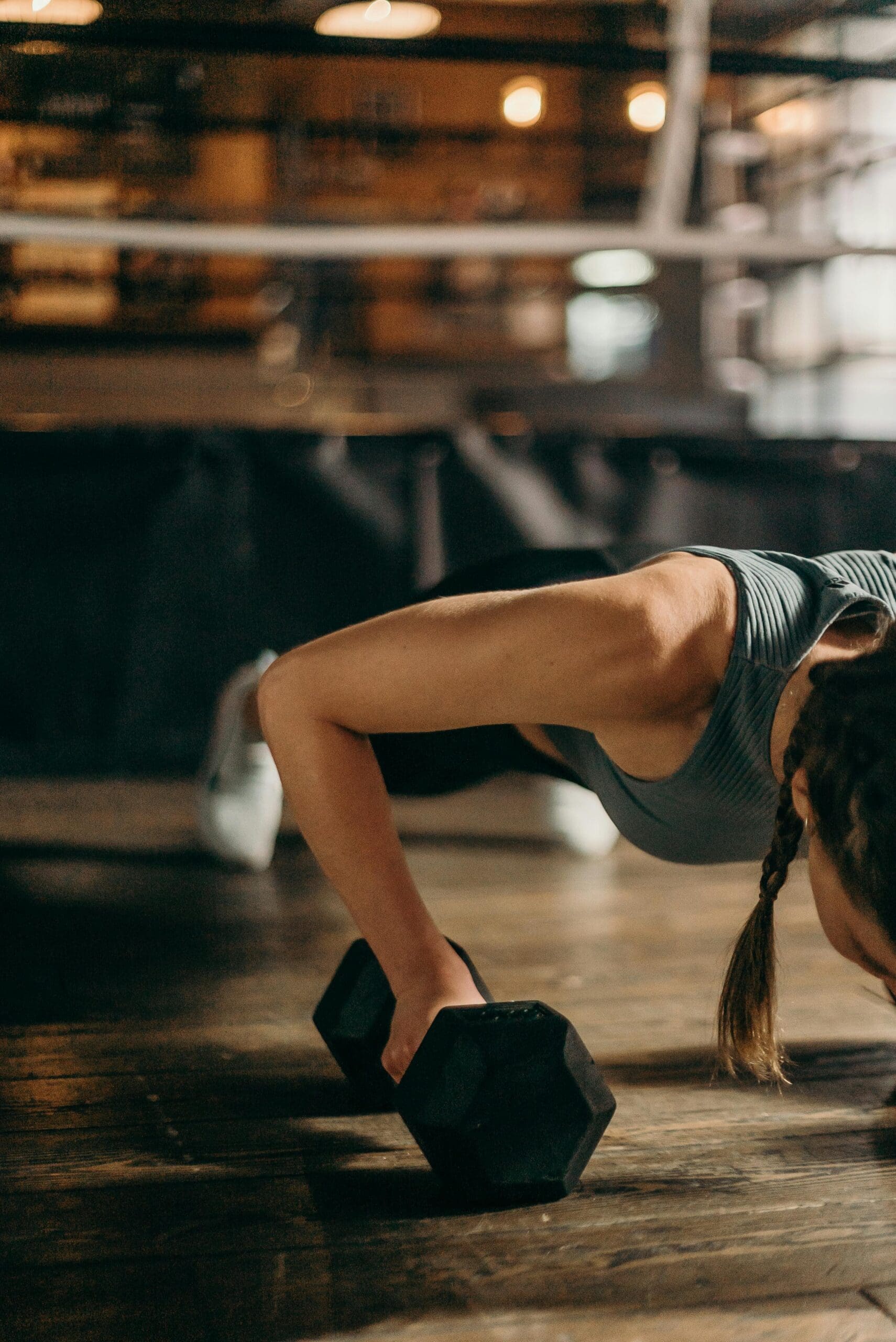 Woman strength training with dumbbell in gym, representing muscle building exercises for maintaining muscle mass after 50