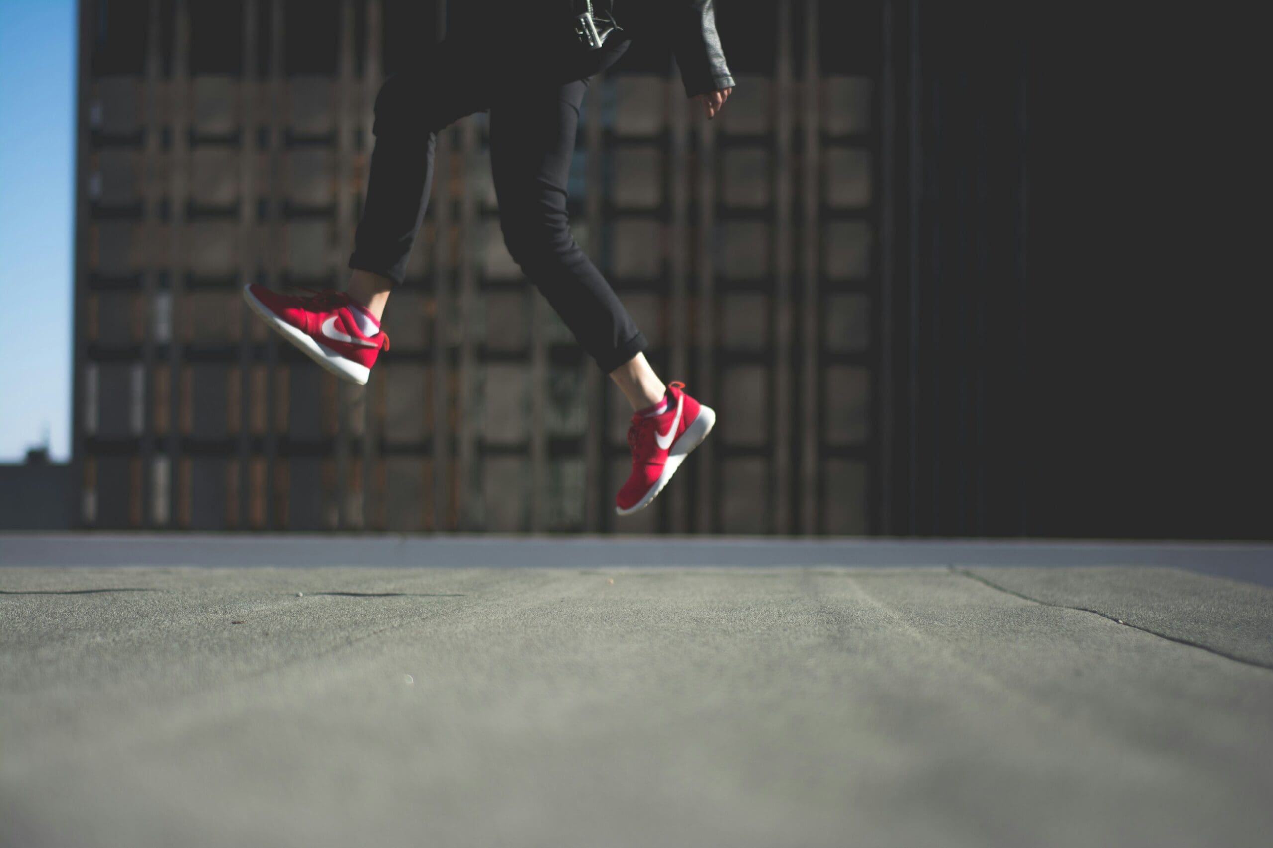 Person jumping outdoors in red sneakers demonstrating simple jumping exercise for bone health