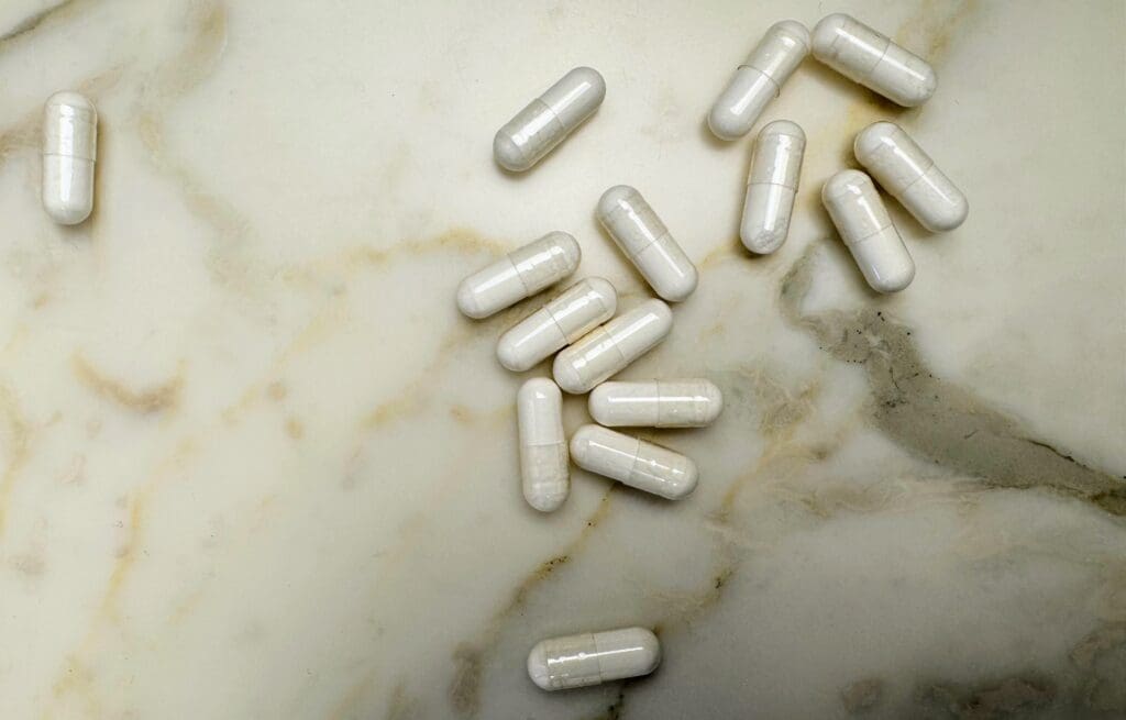 White vitamin D supplement capsules scattered on marble surface showing daily supplementation strategy