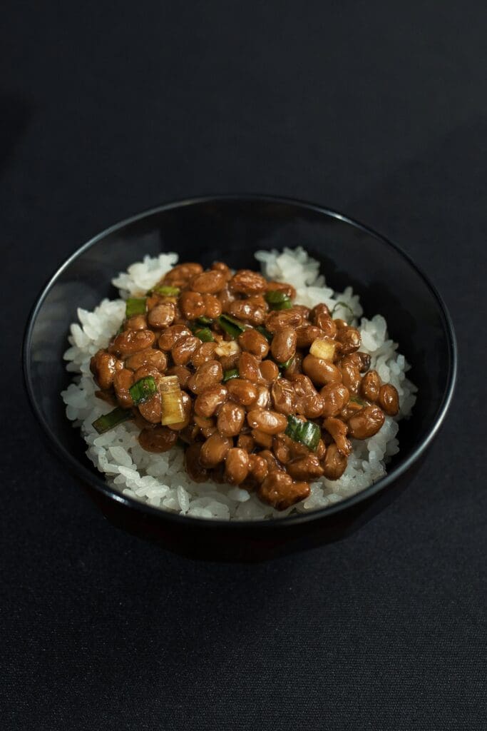 Bowl of natto (fermented soybeans) served over white rice, showing the highest natural food source of vitamin K2 for bone health