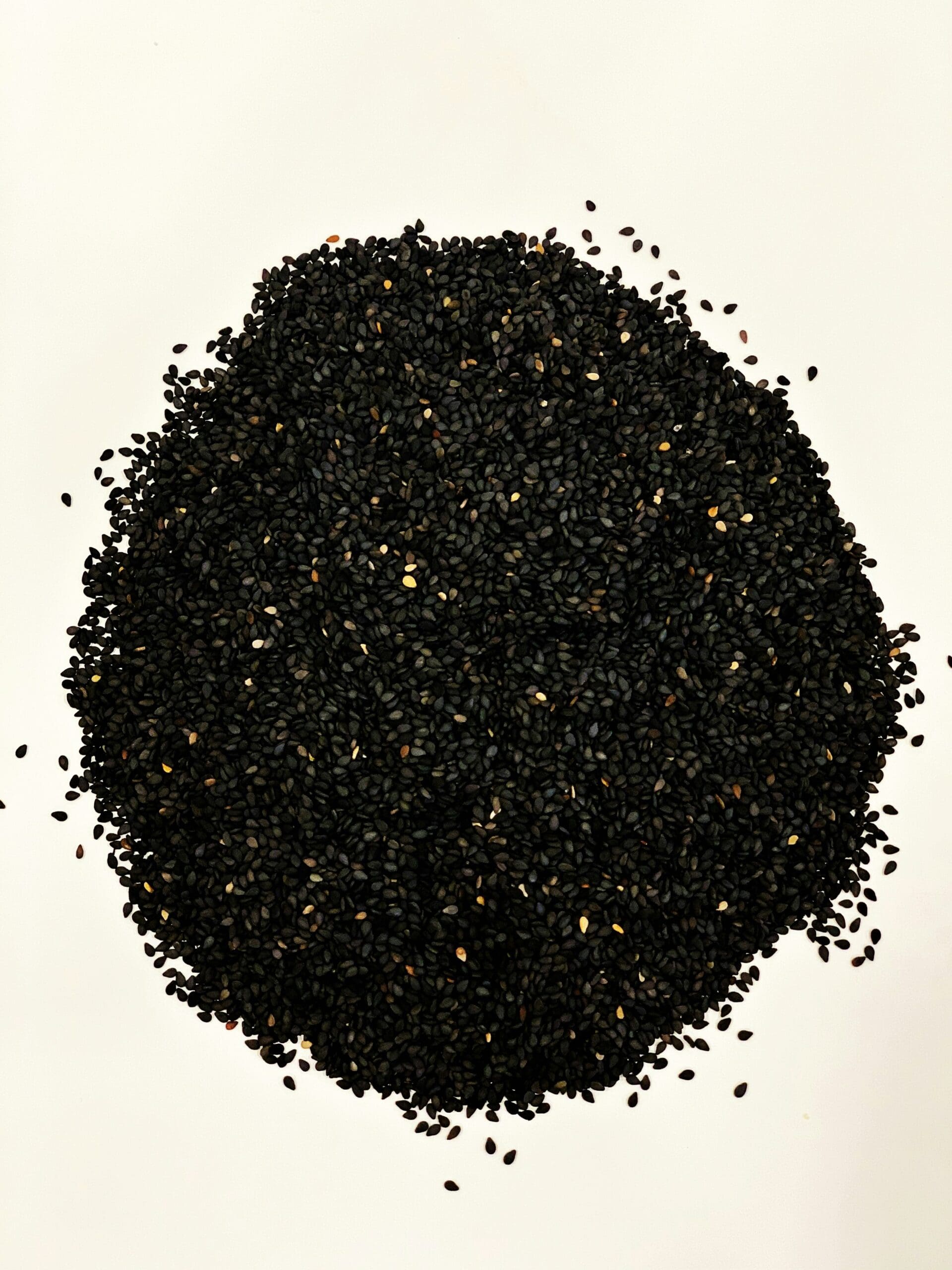 Black sesame seeds on white background showing mineral-dense nutrition source