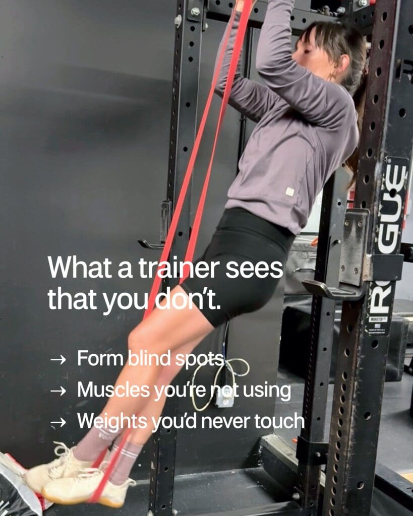 Woman performing resistance band exercise in gym demonstrating proper form with personal trainer guidance