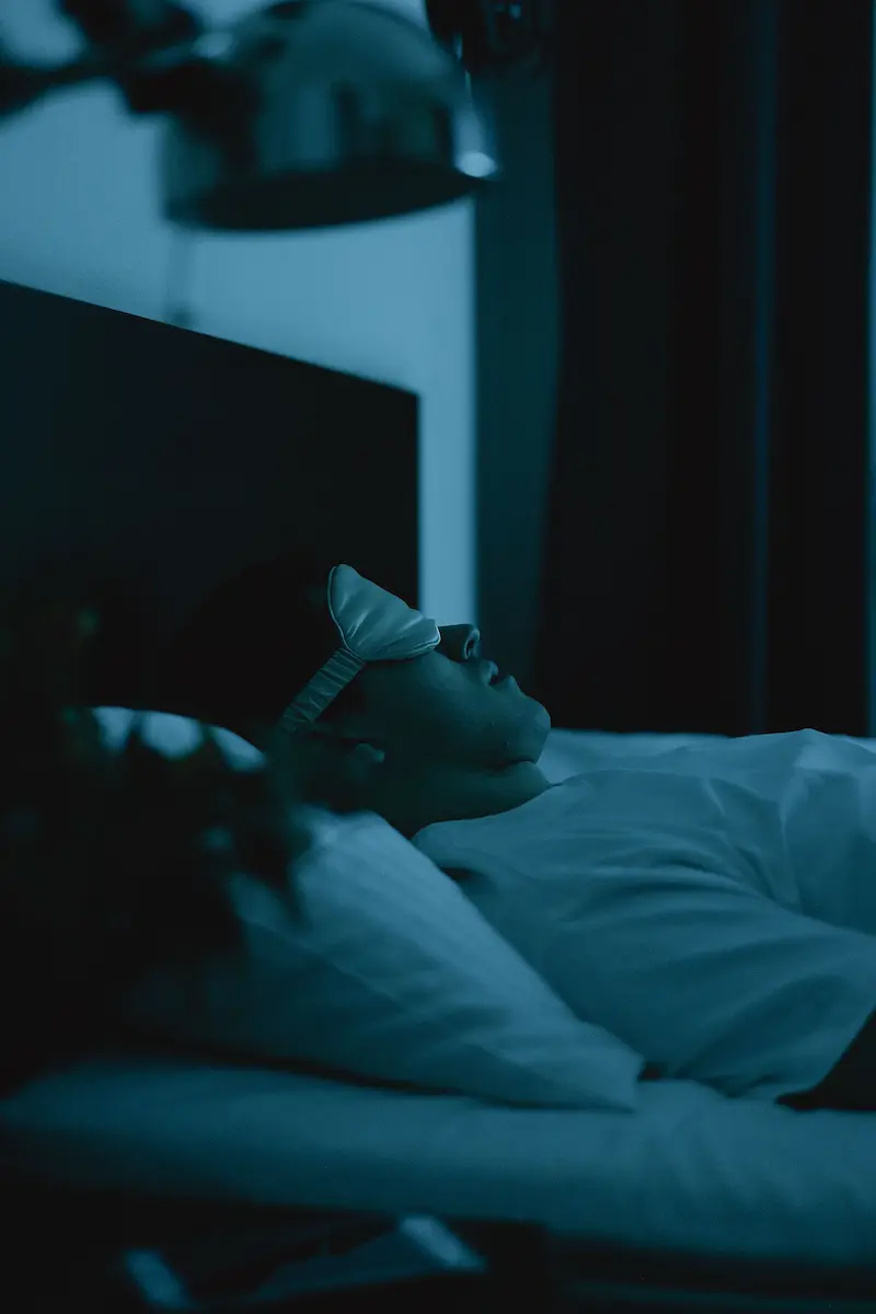 Person sleeping in dark bedroom representing quality sleep for brain health