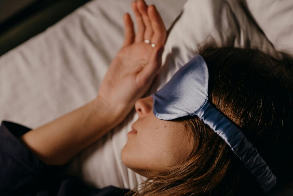 Woman sleeping with eye mask demonstrating quality sleep for muscle recovery
