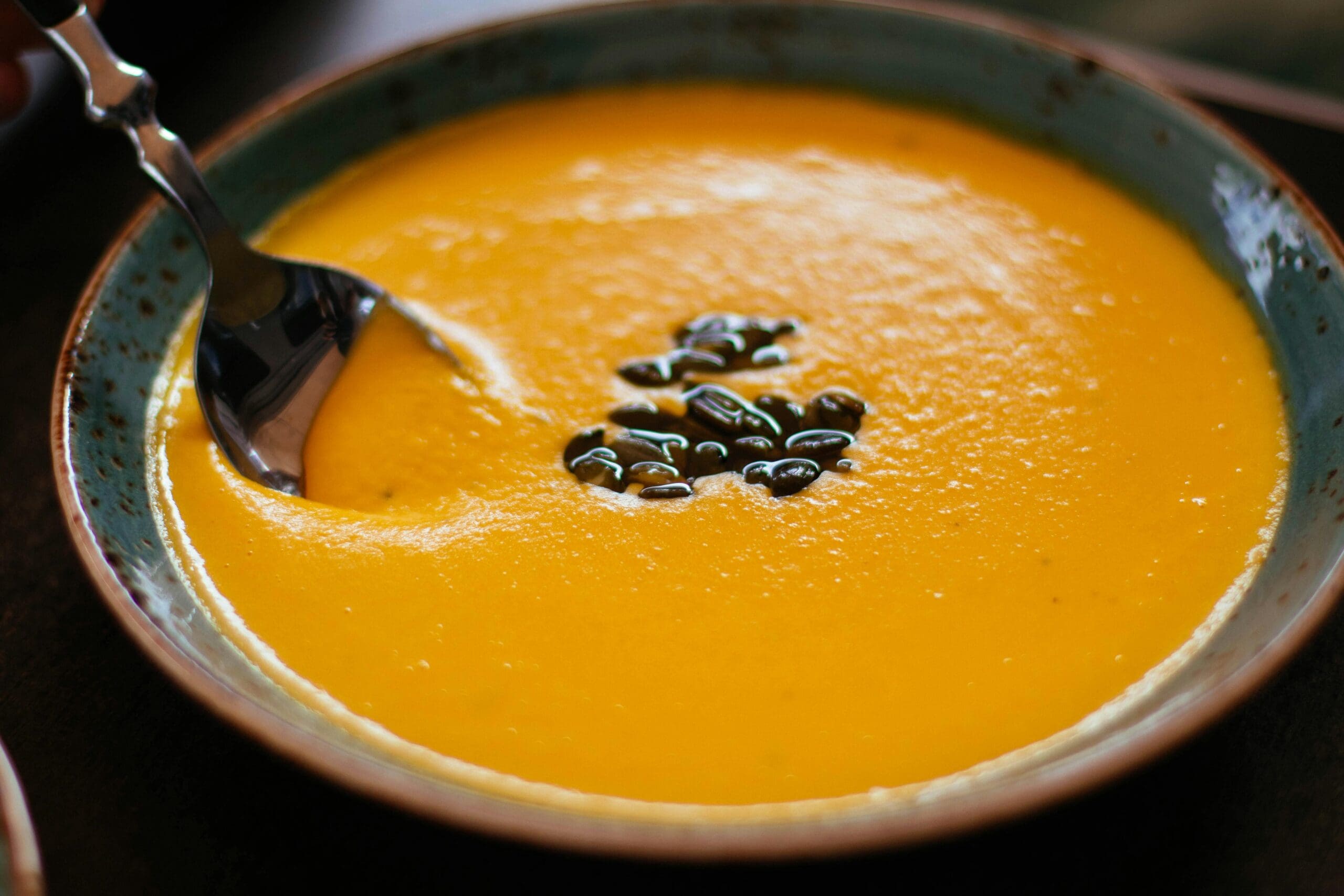 Bowl of creamy pumpkin soup garnished with pepitas showcasing healthy Thanksgiving recipes